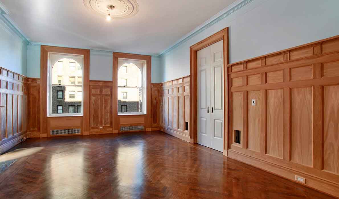 Renovated living room at 390 West End Avenue apartments in NYC, featuring restored wood paneling, hardwood floors, and elegant trim work by Universal Management & Contracting Corp, a New York City construction and renovation company.