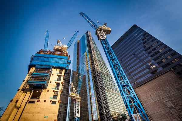 High-rise commercial building construction in NYC with cranes and skyscrapers