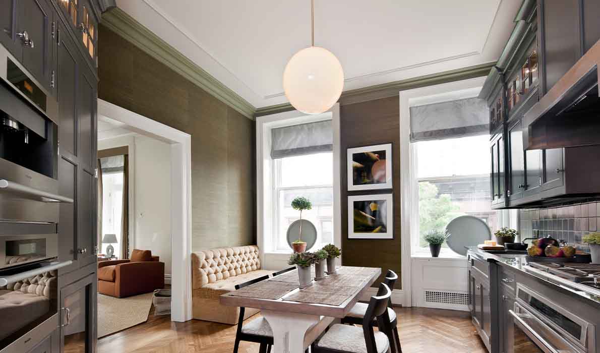 High-end kitchen renovation at 390 West End Ave apartments in NYC by Universal Management & Contracting Corp, featuring custom cabinetry, luxury appliances, herringbone wood floors, and elegant dining nook.