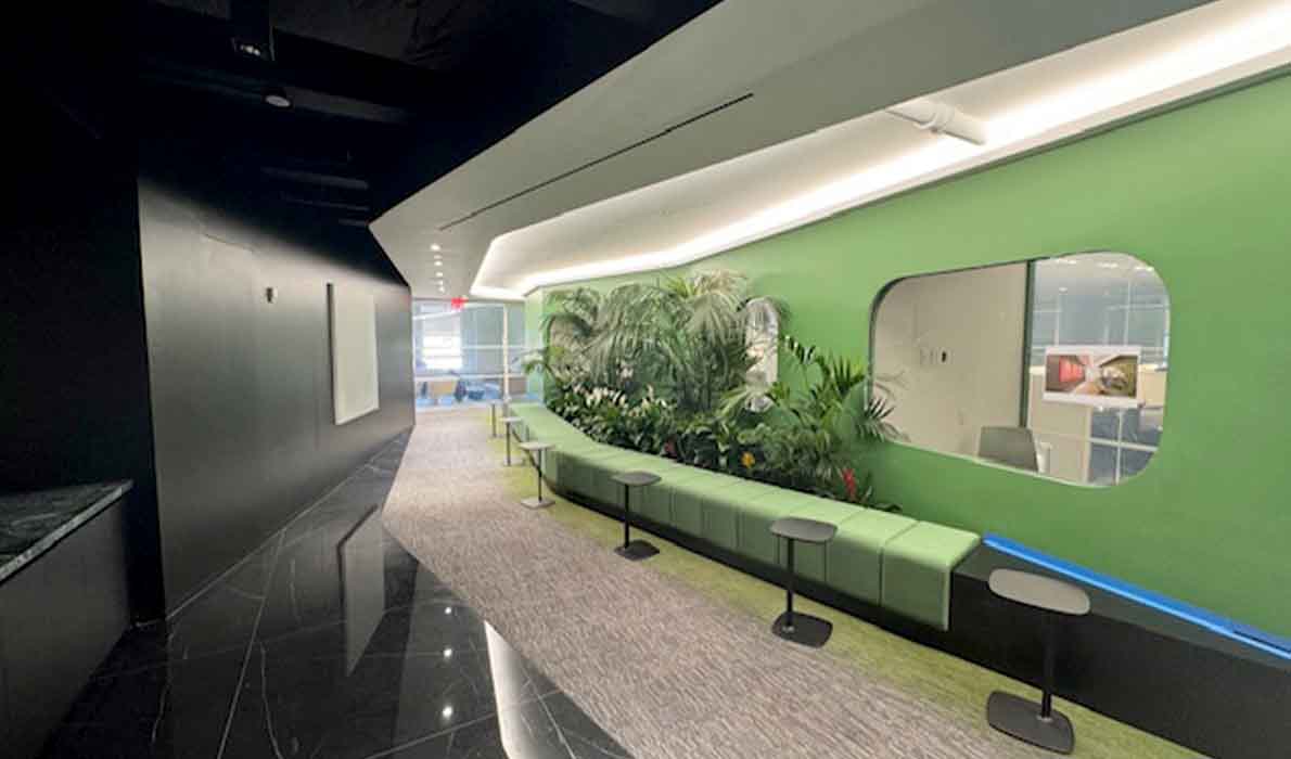 Modern office hallway with green accent wall, indoor plants, and sleek seating area designed and built by Universal Management and Contracting, NYC commercial renovation specialists.
