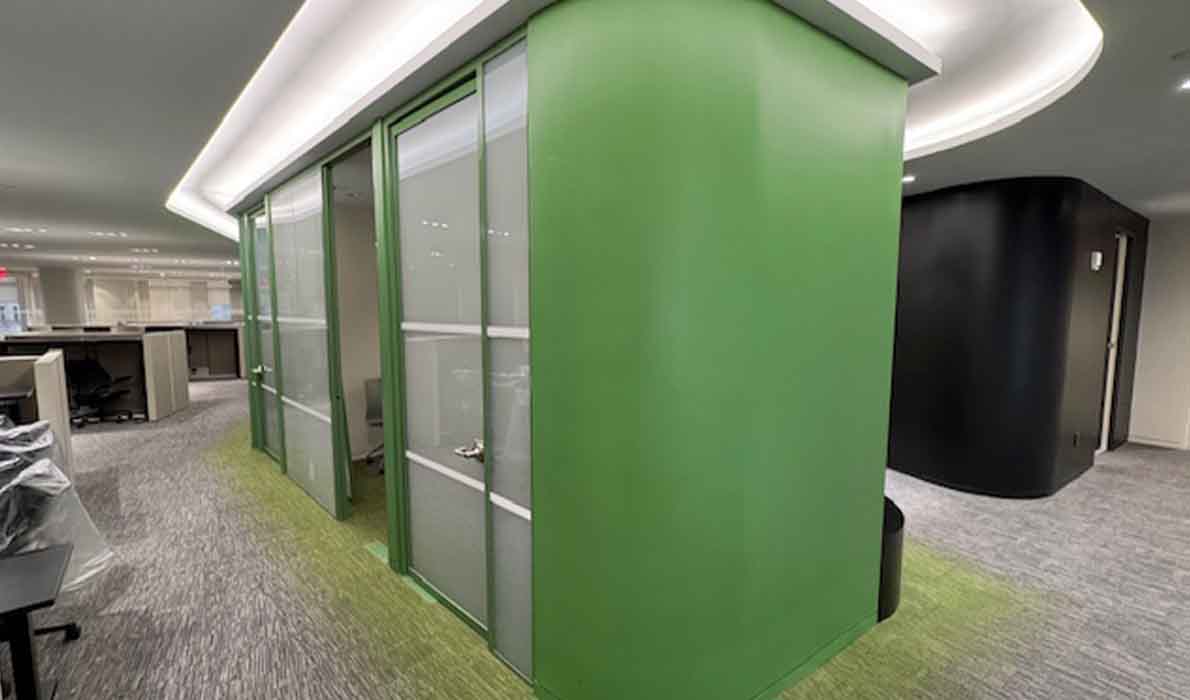 Sleek modern office interior construction in NYC by Universal Management, featuring curved green architectural walls and contemporary lighting design.